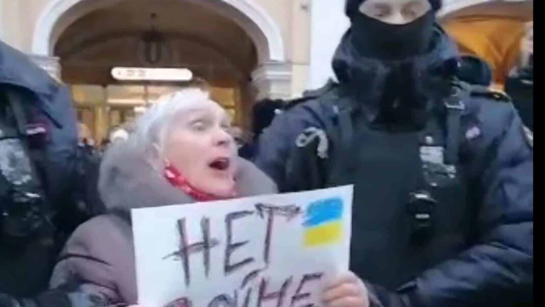 une femme âgée aux cheveux blancs tient une affiche contre la guerre en Ukraine arrêtée par deux policiers russes